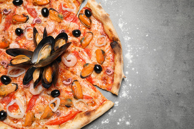 Photo of Tasty pizza with seafood on grey table, top view. Space for text