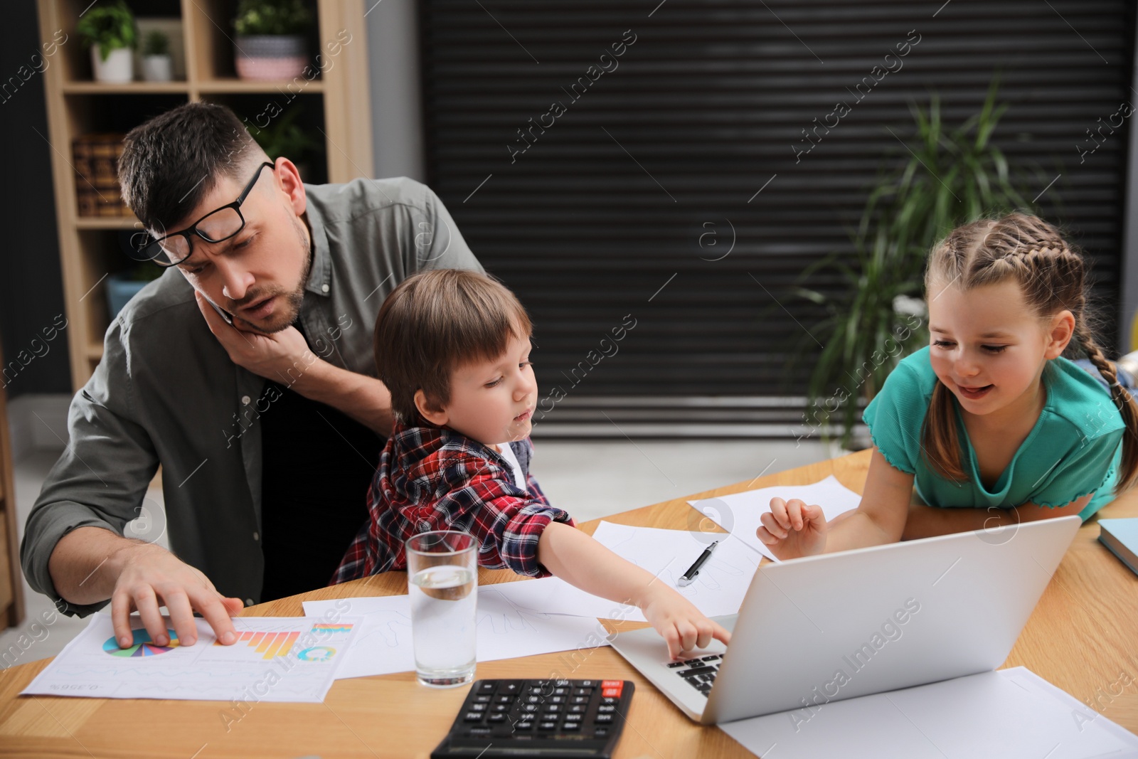 Photo of Overwhelmed man combining parenting and work at home