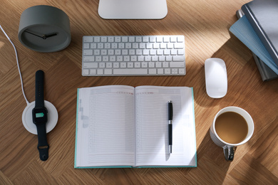 Modern workplace and watch charging with wireless pad, flat lay