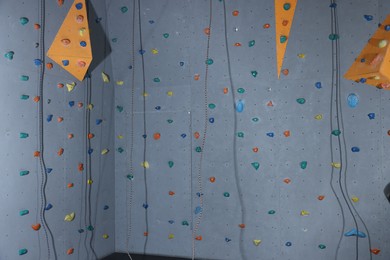 Climbing wall with holds and ropes in gym. Extreme sport