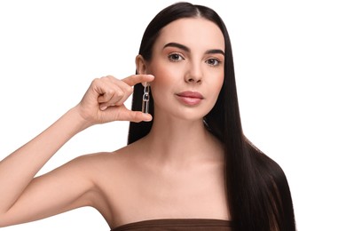 Beautiful young woman holding skincare ampoule on white background