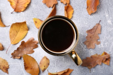 Photo of Flat lay composition with cup of hot drink and autumn leaves on light grey textured table