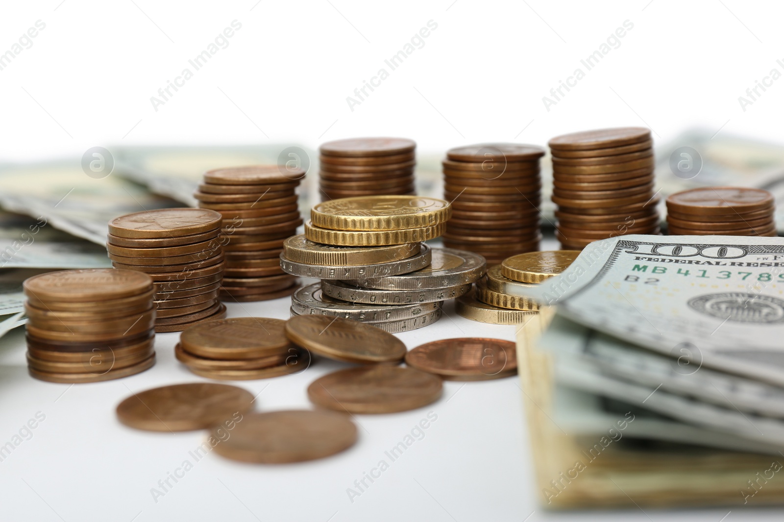 Photo of Dollar banknotes and stacks of coins on white background, closeup