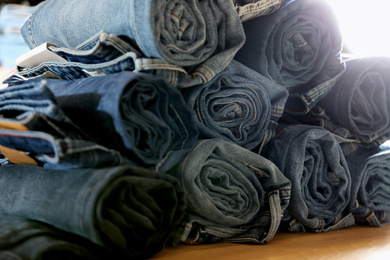 Photo of Rolled modern jeans on display in shop, closeup