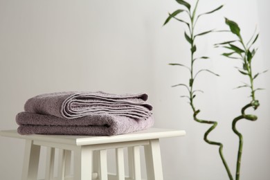 Violet towels on stool against white wall. Space for text