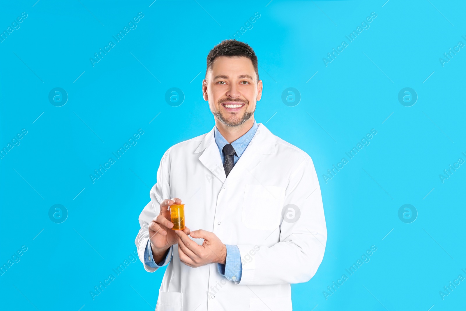 Photo of Professional pharmacist with pills on light blue background