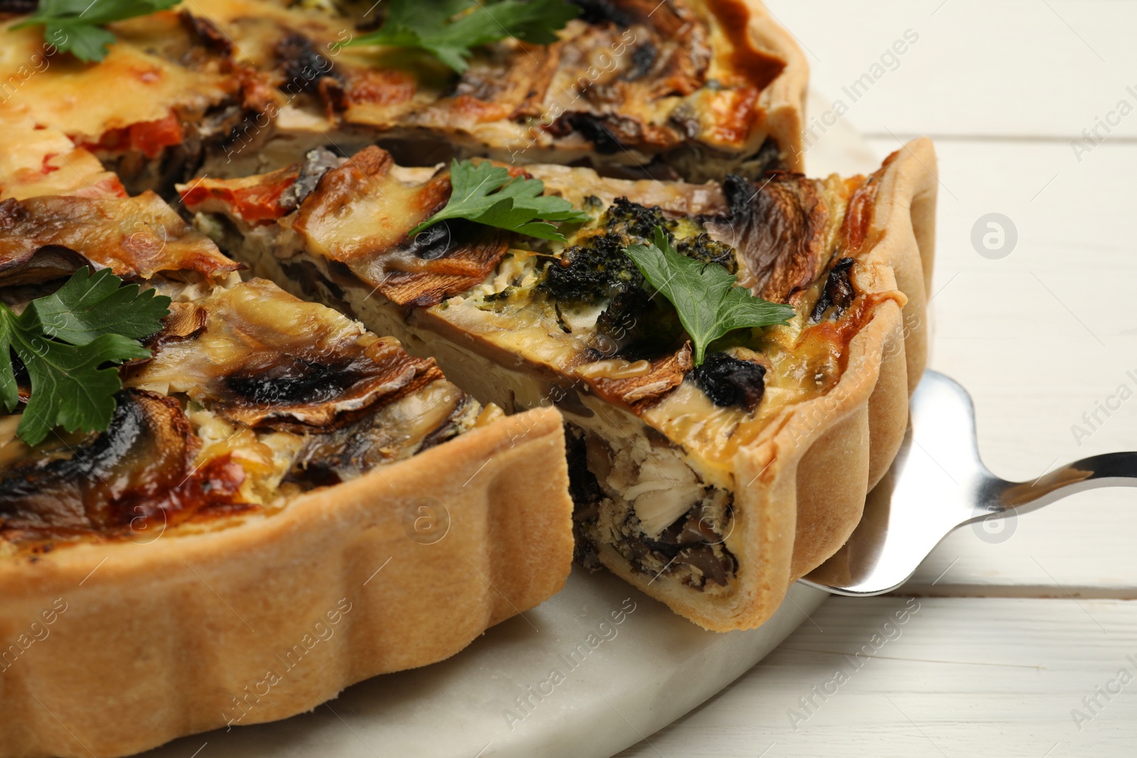 Photo of Delicious quiche with mushrooms and spatula on white wooden table, closeup