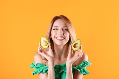 Portrait of young beautiful woman with ripe delicious avocado on color background