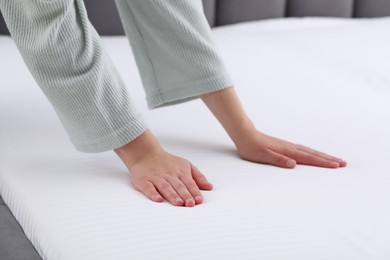 Photo of Woman touching white soft mattress, closeup view