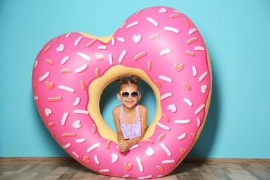 Photo of Cute little girl with inflatable heart near color wall
