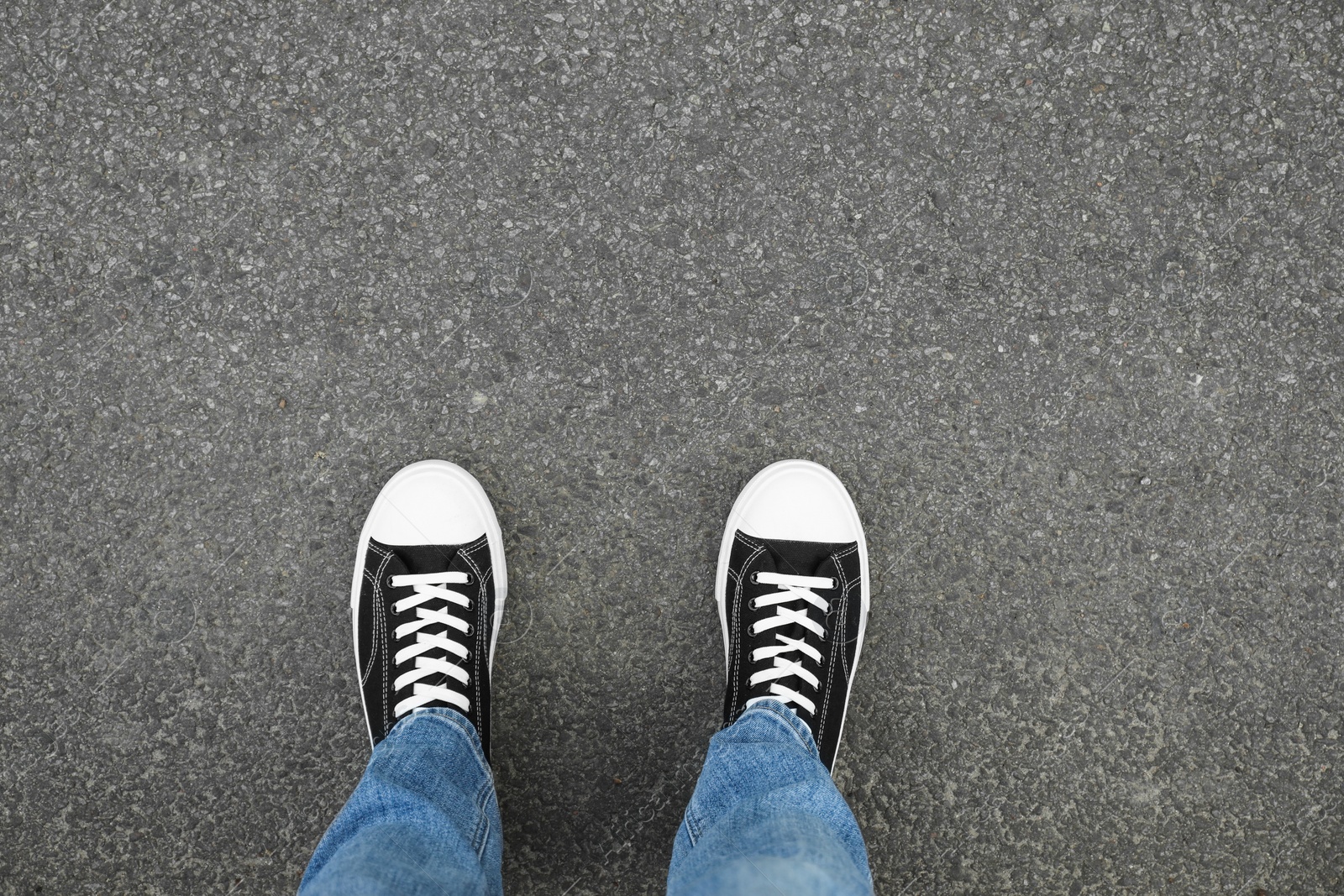 Photo of Man in sneakers standing on asphalt, top view. Space for text