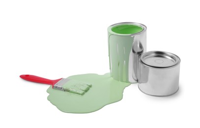 Photo of Spilled light green paint, brush and cans on white background
