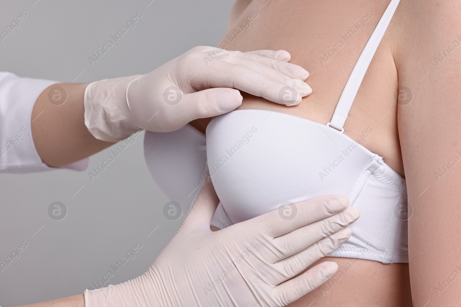 Photo of Mammologist checking woman's breast on gray background, closeup