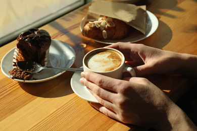 Photo of Woman with cup of fresh aromatic coffee at table in cafe