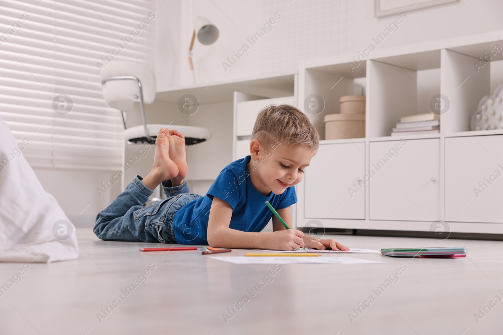 Photo of Cute little boy drawing on warm floor at home. Heating system