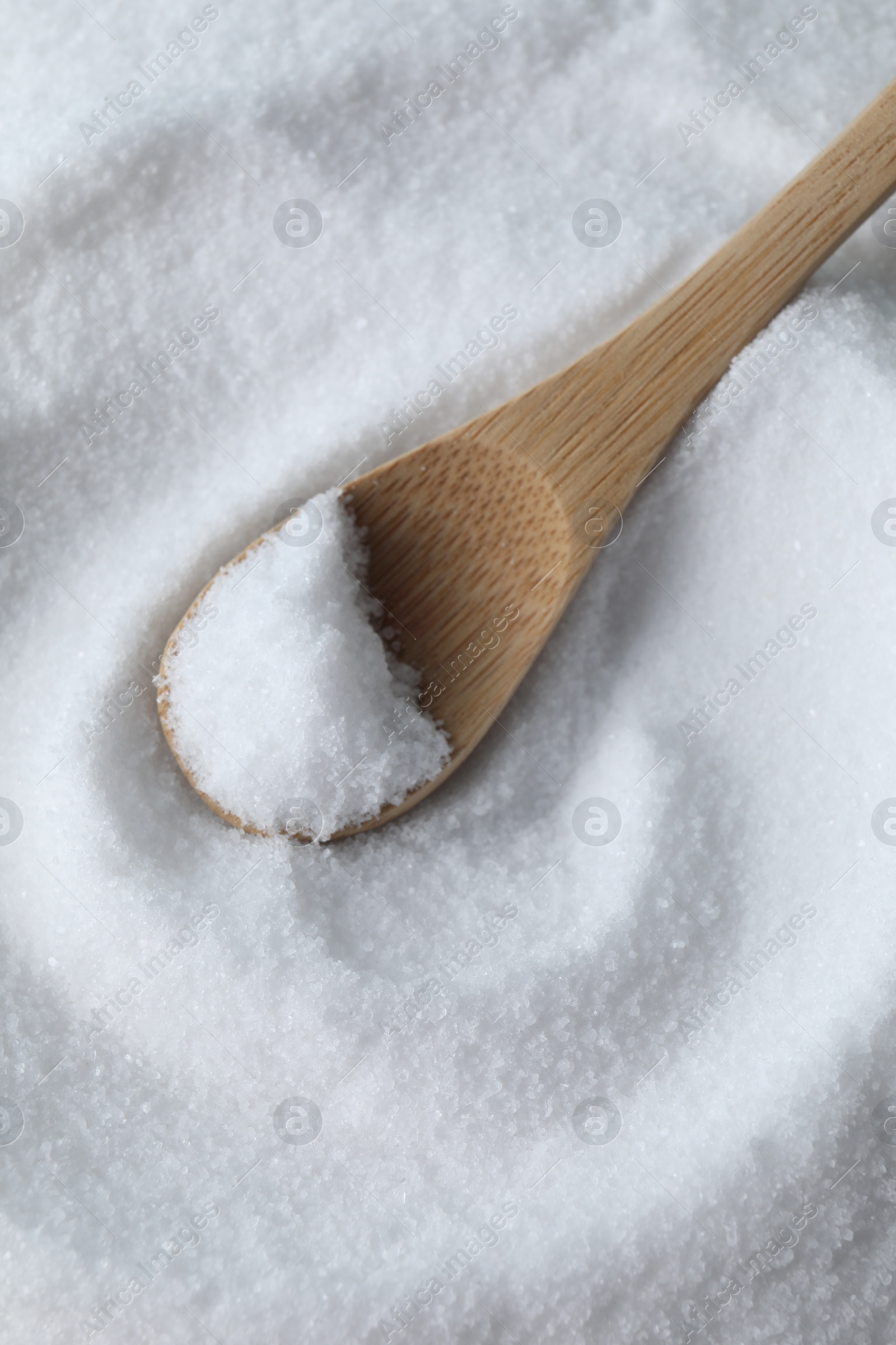 Photo of Wooden spoon on white sea salt, top view