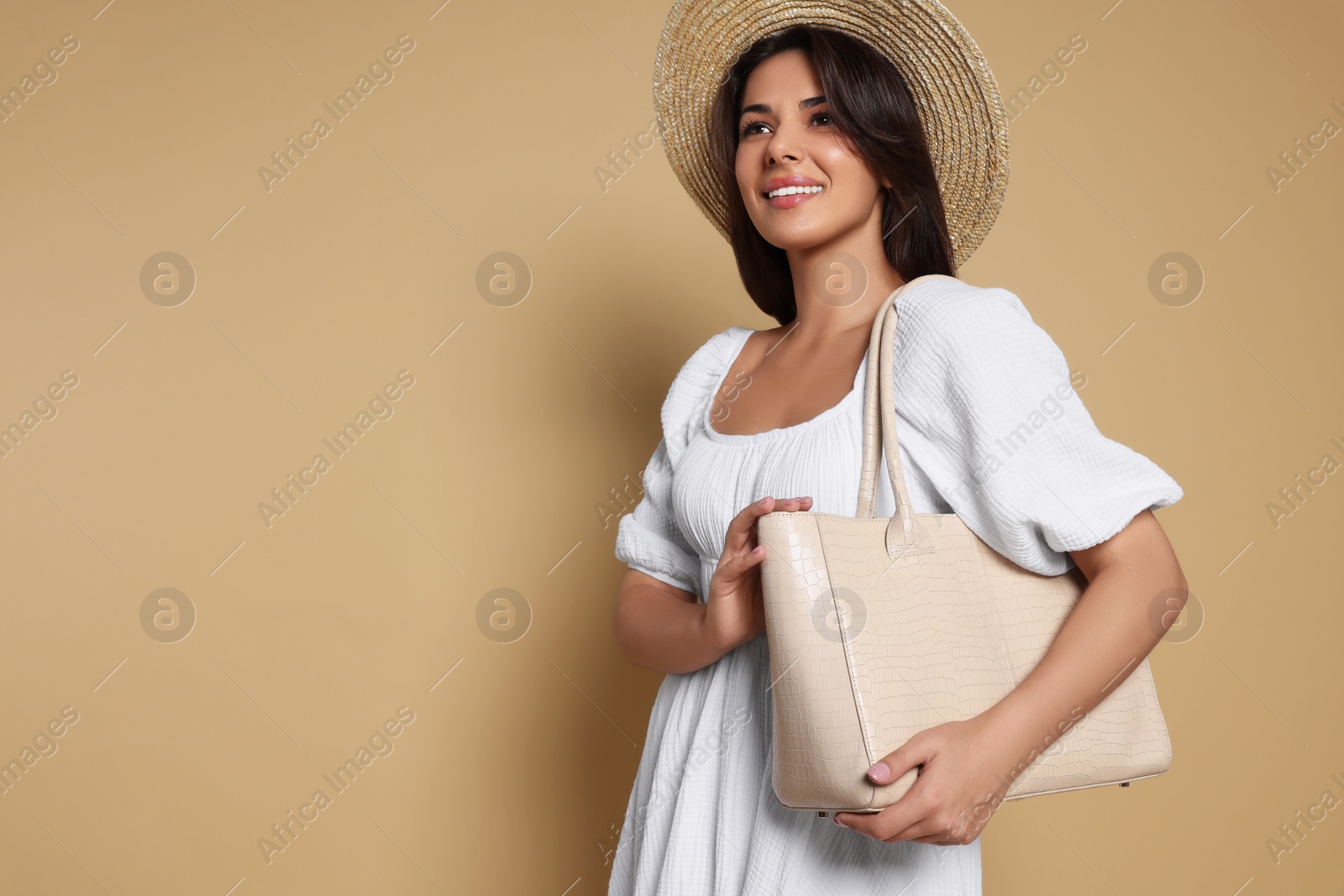 Photo of Young woman with stylish bag on beige background, space for text