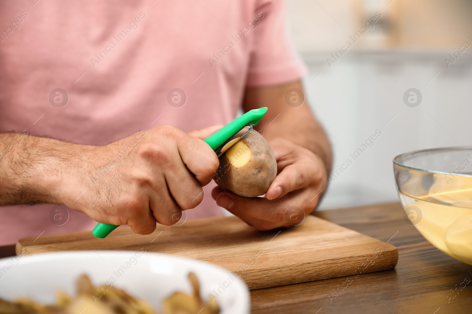 Photo of Man peeling potato at table, closeup. Preparing vegetable