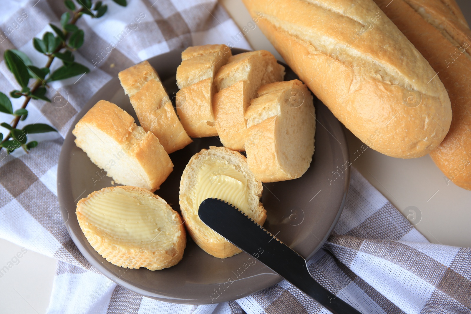 Photo of Whole and cut baguettes with fresh butter on table, above view