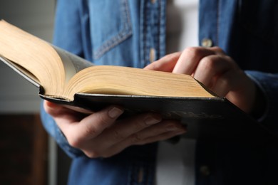 Woman reading old holy Bible on blurred background, closeup