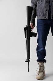 Assault gun. Man holding rifle on light background, closeup