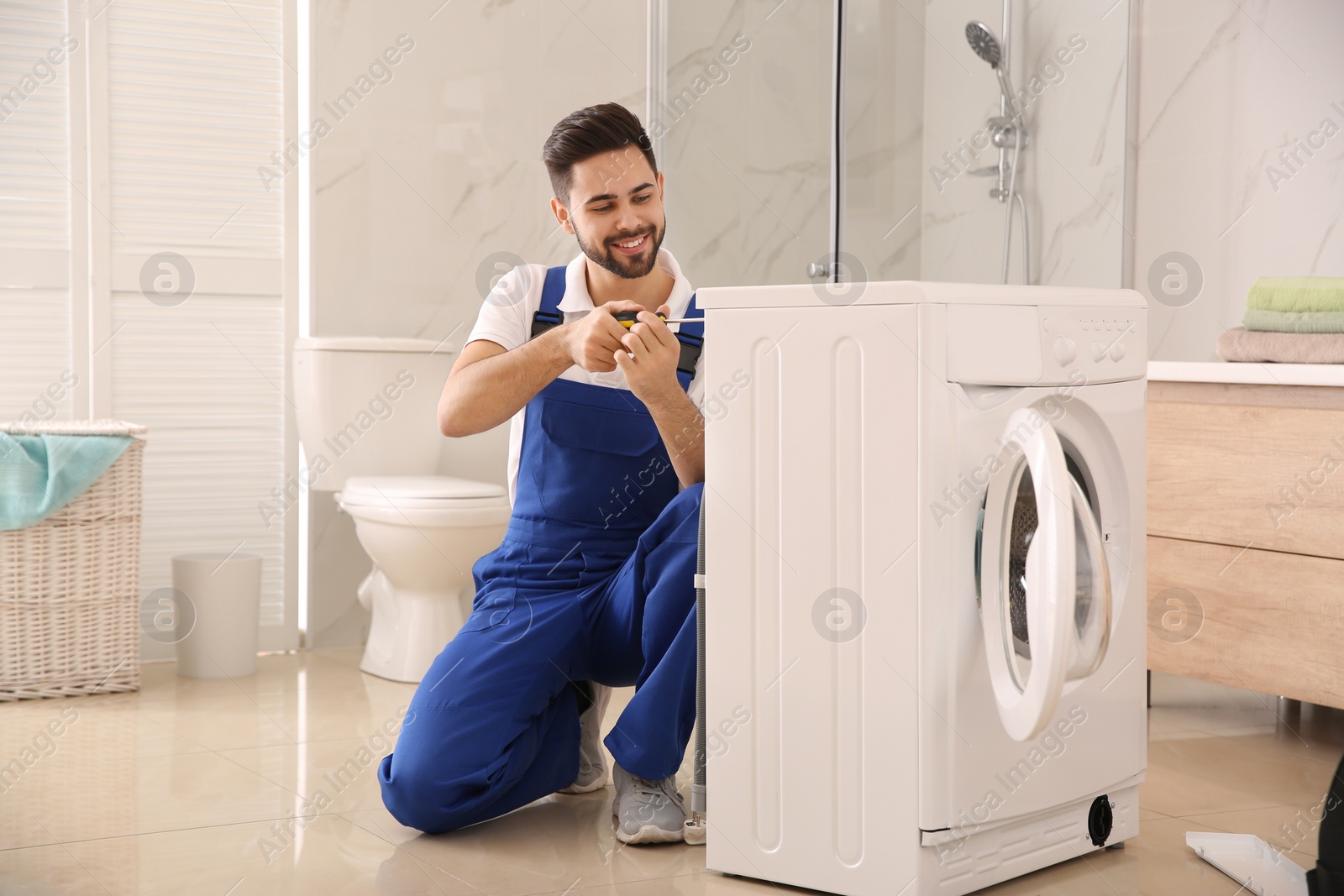 Photo of Professional plumber repairing washing machine in bathroom