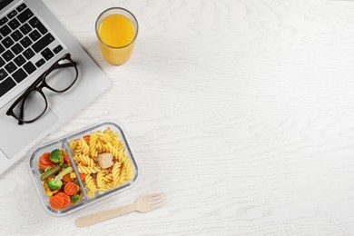 Container of tasty food, fork, laptop, glass of juice on white wooden table, flat lay with space for text. Business lunch