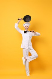 Photo of Professional chef with wok and spatula having fun on yellow background