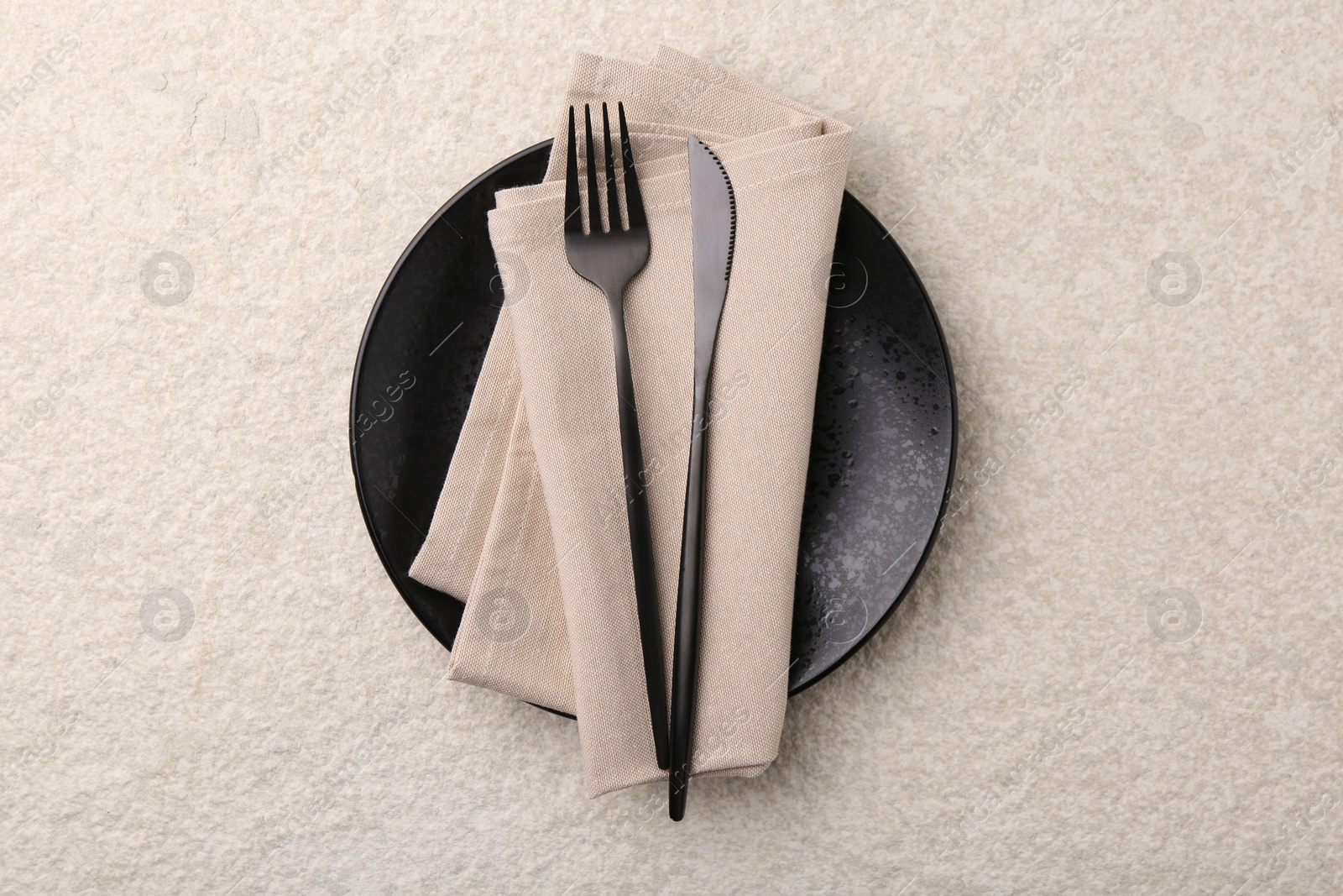 Photo of Stylish setting with elegant cutlery on beige textured table, top view