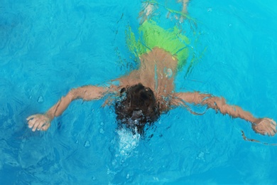 Little child under water in outdoor swimming pool. Dangerous situation