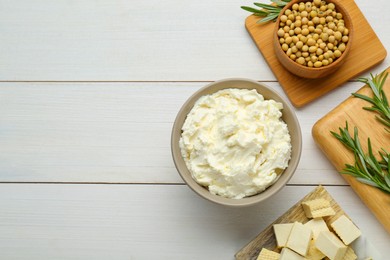 Photo of Delicious tofu cheese, soy beans and rosemary on white wooden table, flat lay. Space for text