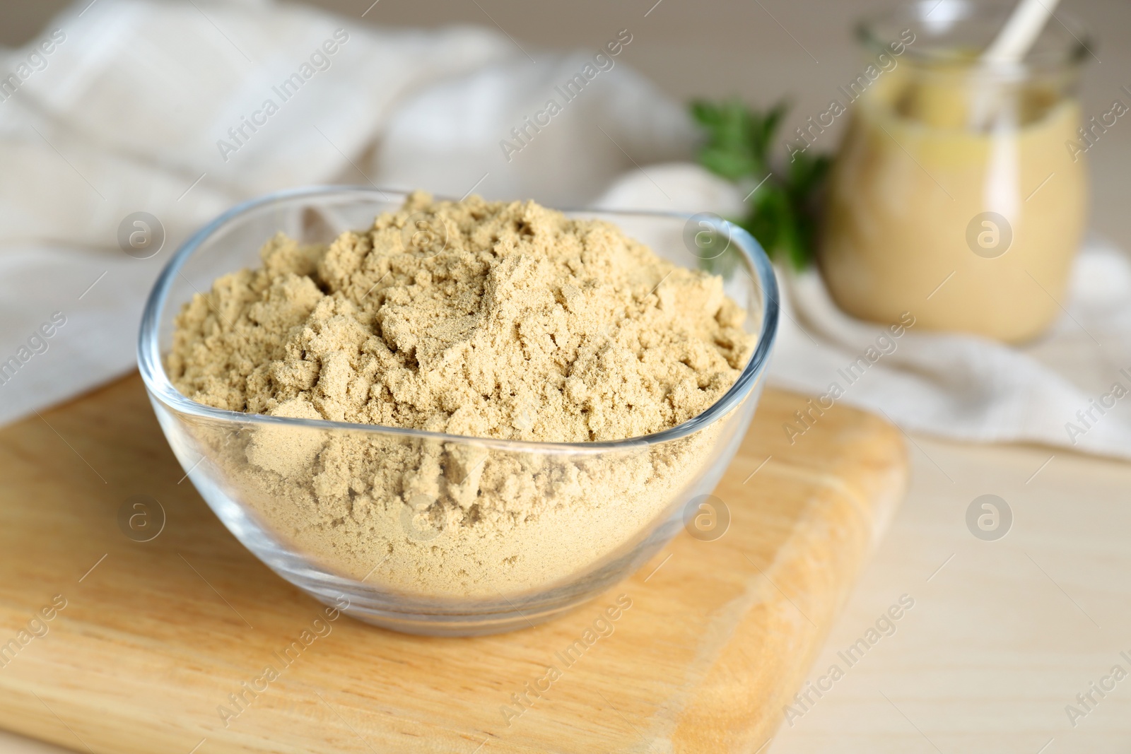 Photo of Bowl of aromatic mustard powder on wooden table, closeup