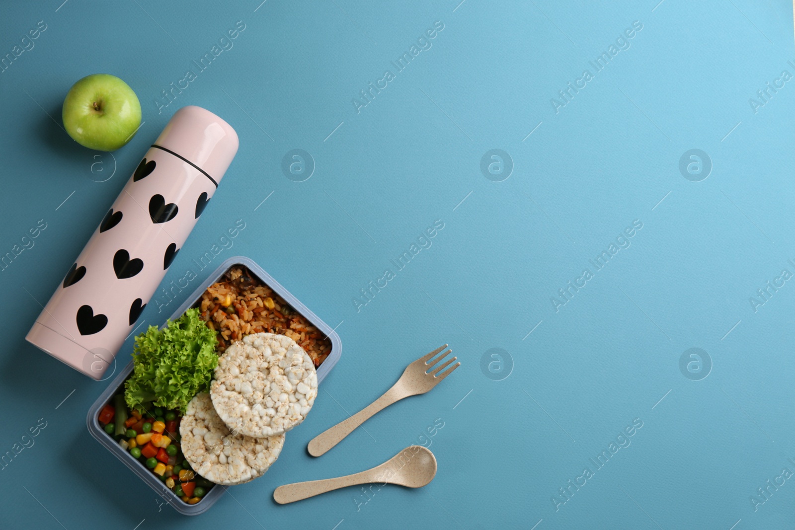 Photo of Thermos and lunch box with food on light blue background, flat lay. Space for text