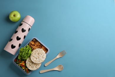 Photo of Thermos and lunch box with food on light blue background, flat lay. Space for text
