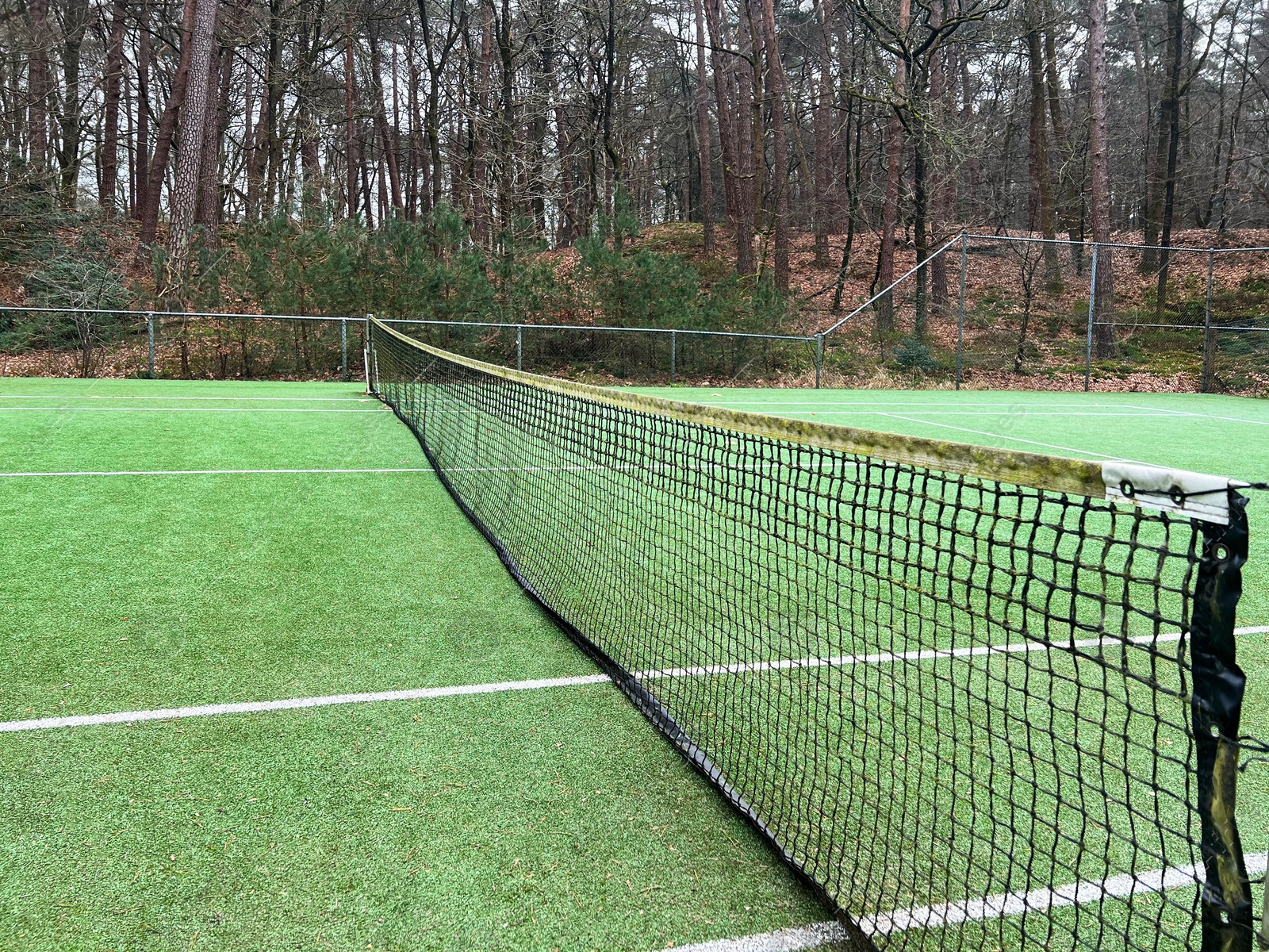 Photo of Tennis court with artificial grass and net outdoors