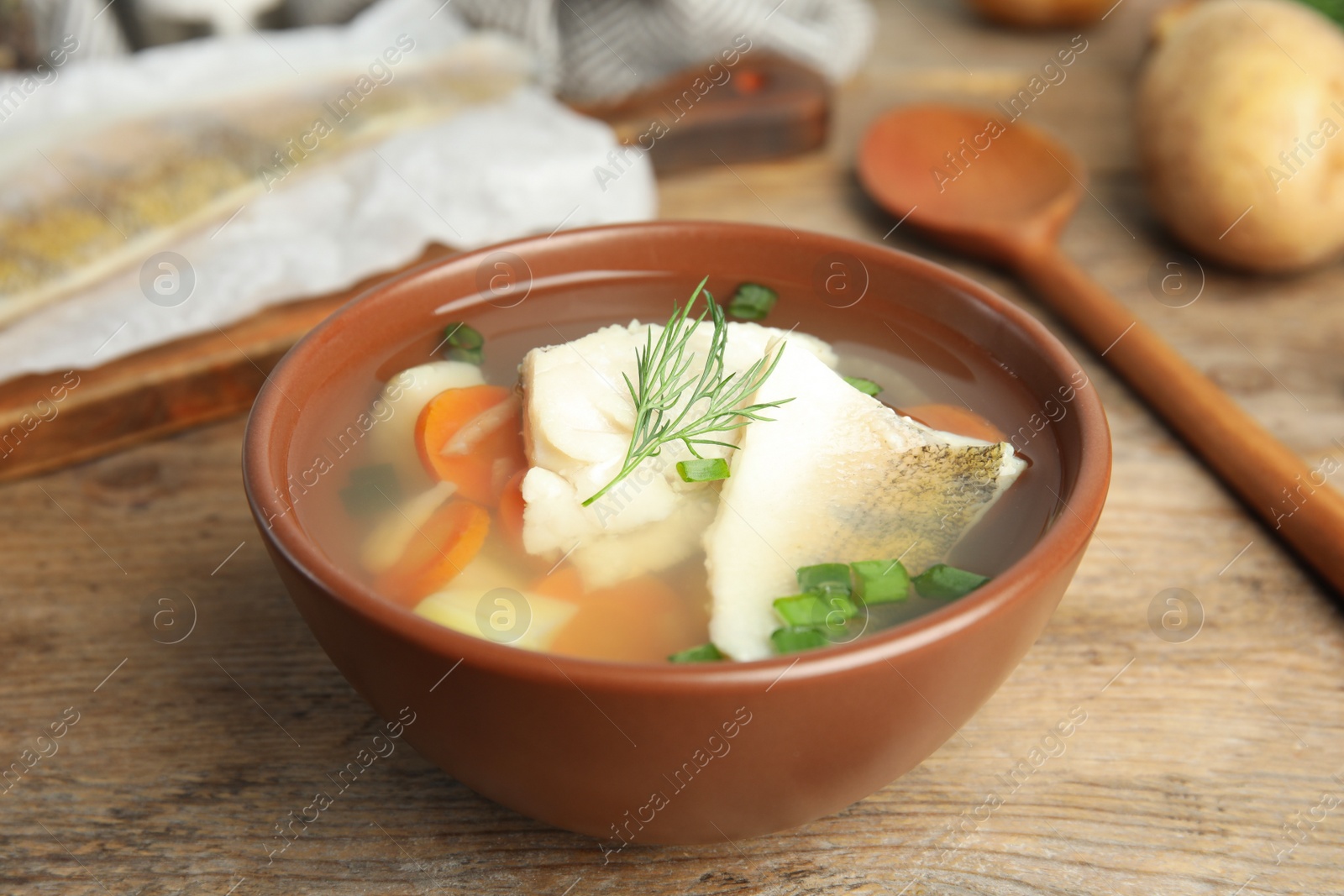 Photo of Delicious fish soup in bowl on wooden table