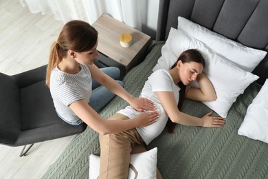 Photo of Doula working with pregnant woman in bedroom, top view. Preparation for child birth