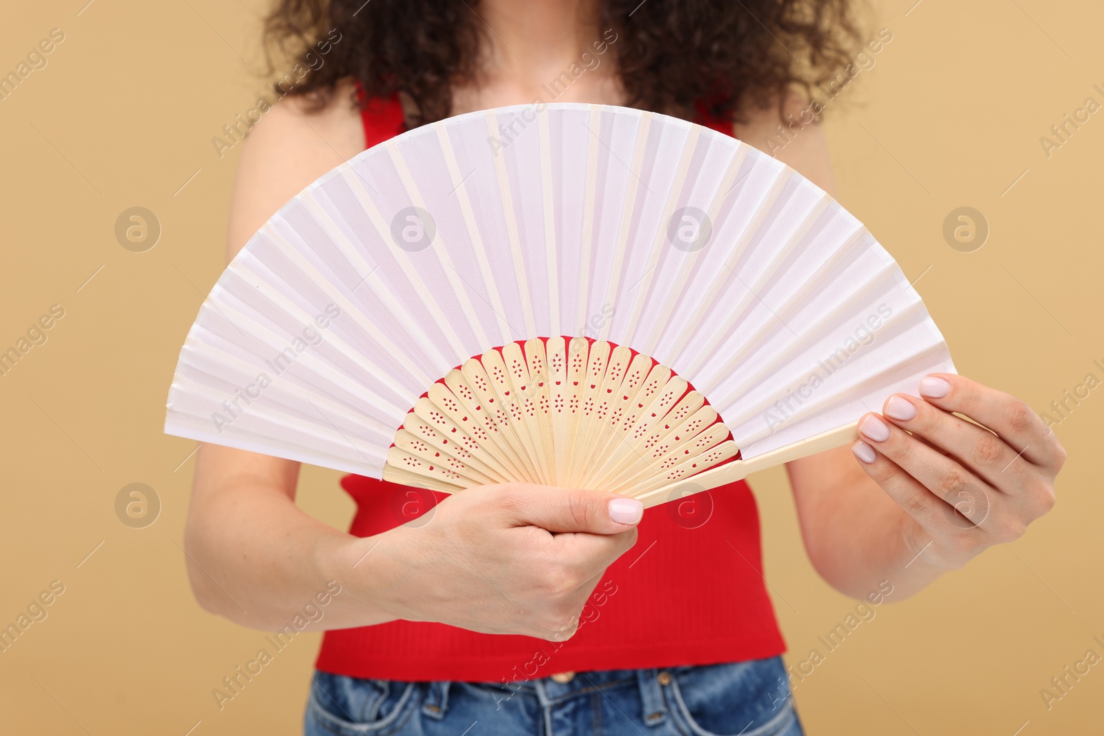 Photo of Woman holding hand fan on beige background, closeup