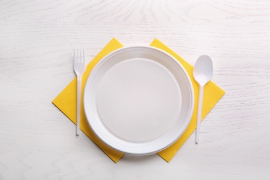 Composition with plastic dishware on wooden table, flat lay. Picnic table setting