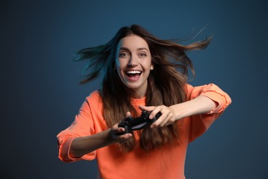 Photo of Emotional woman playing video game with controller on dark blue background