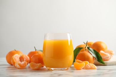 Glass of fresh tangerine juice and fruits on marble table