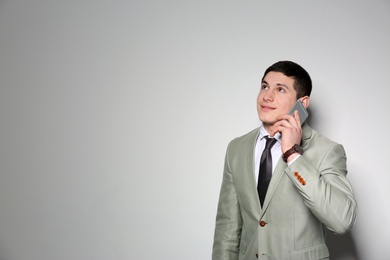 Photo of Portrait of young businessman talking on phone against light background. Space for text