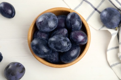 Delicious ripe plums on white wooden table, flat lay