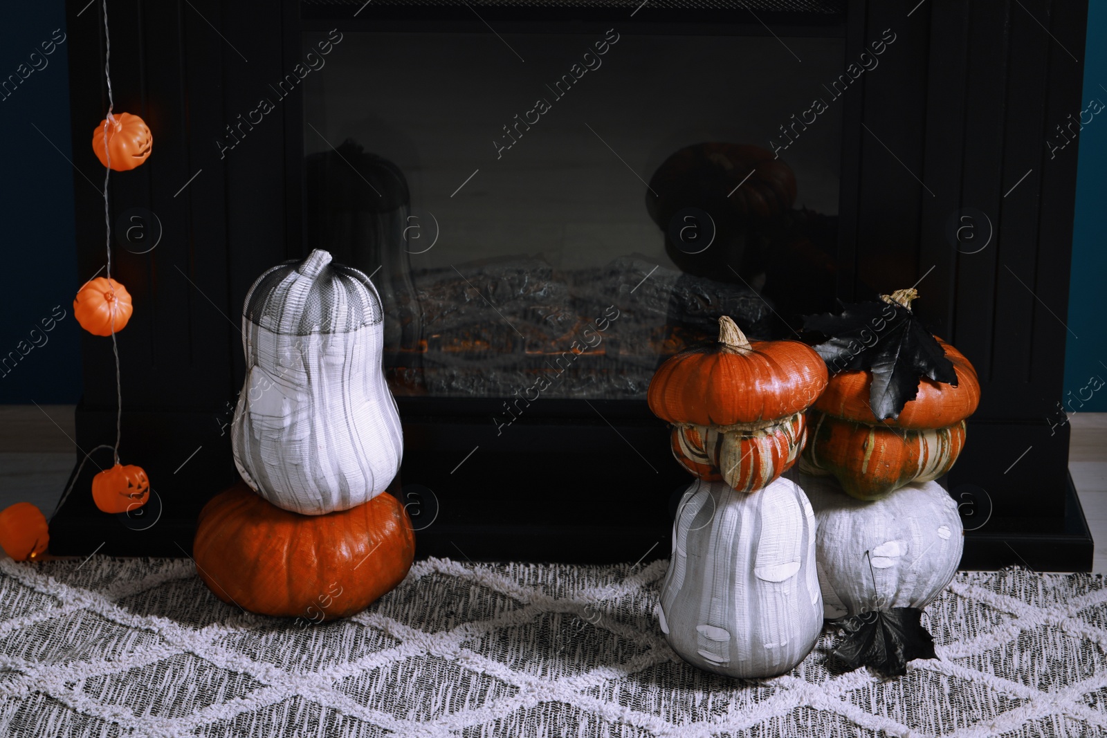 Photo of Colorful pumpkins on rug near fireplace. Halloween decorations