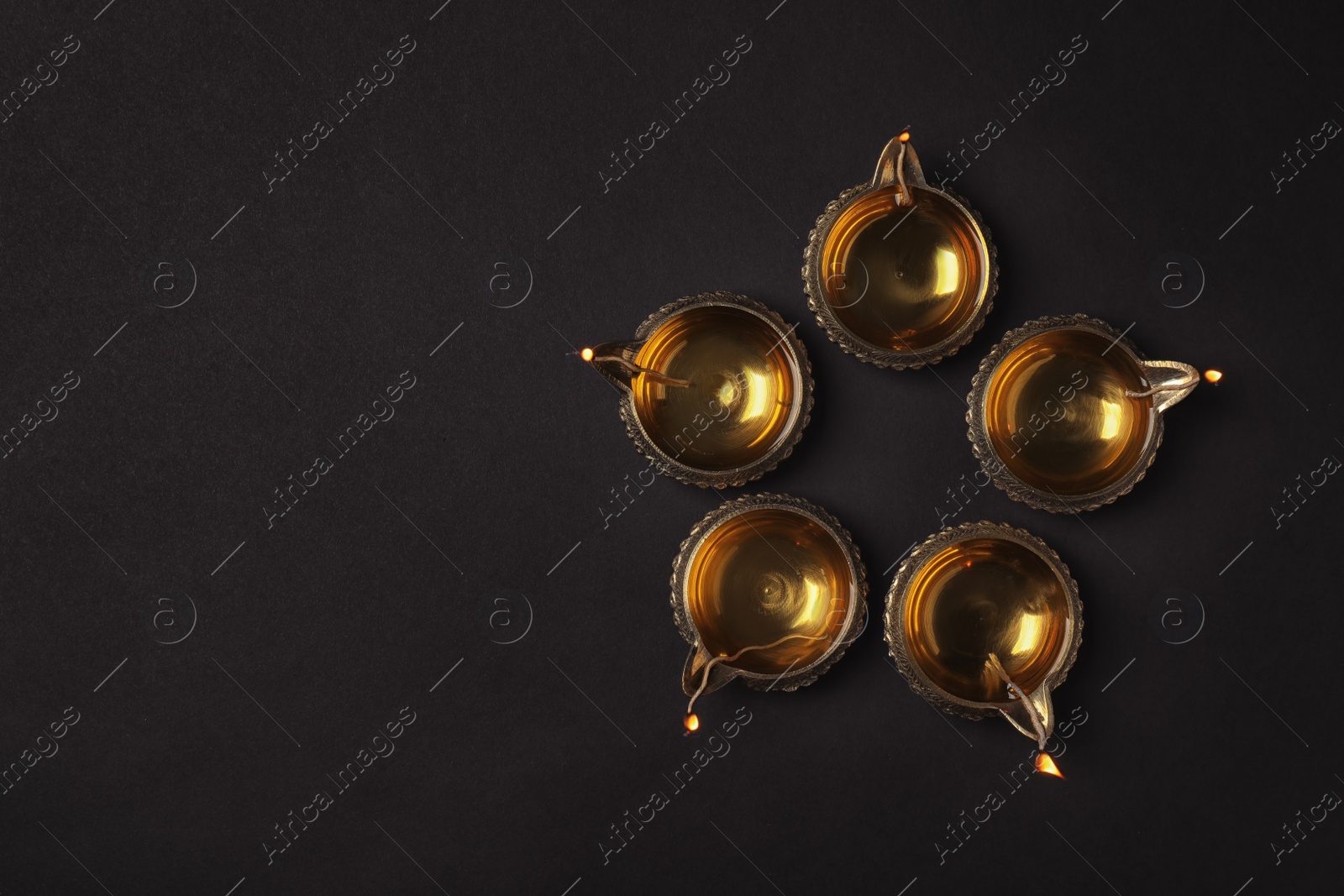 Photo of Diwali diyas or clay lamps on dark background, top view