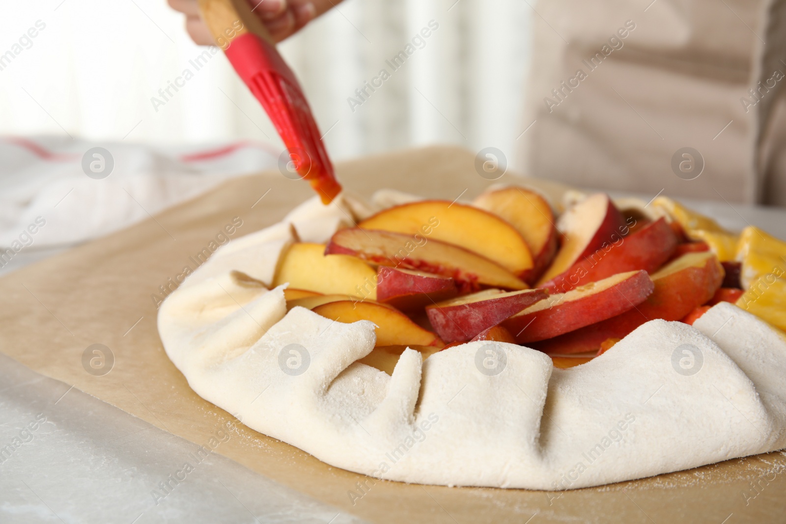 Photo of Woman making peach pie at kitchen table, closeup