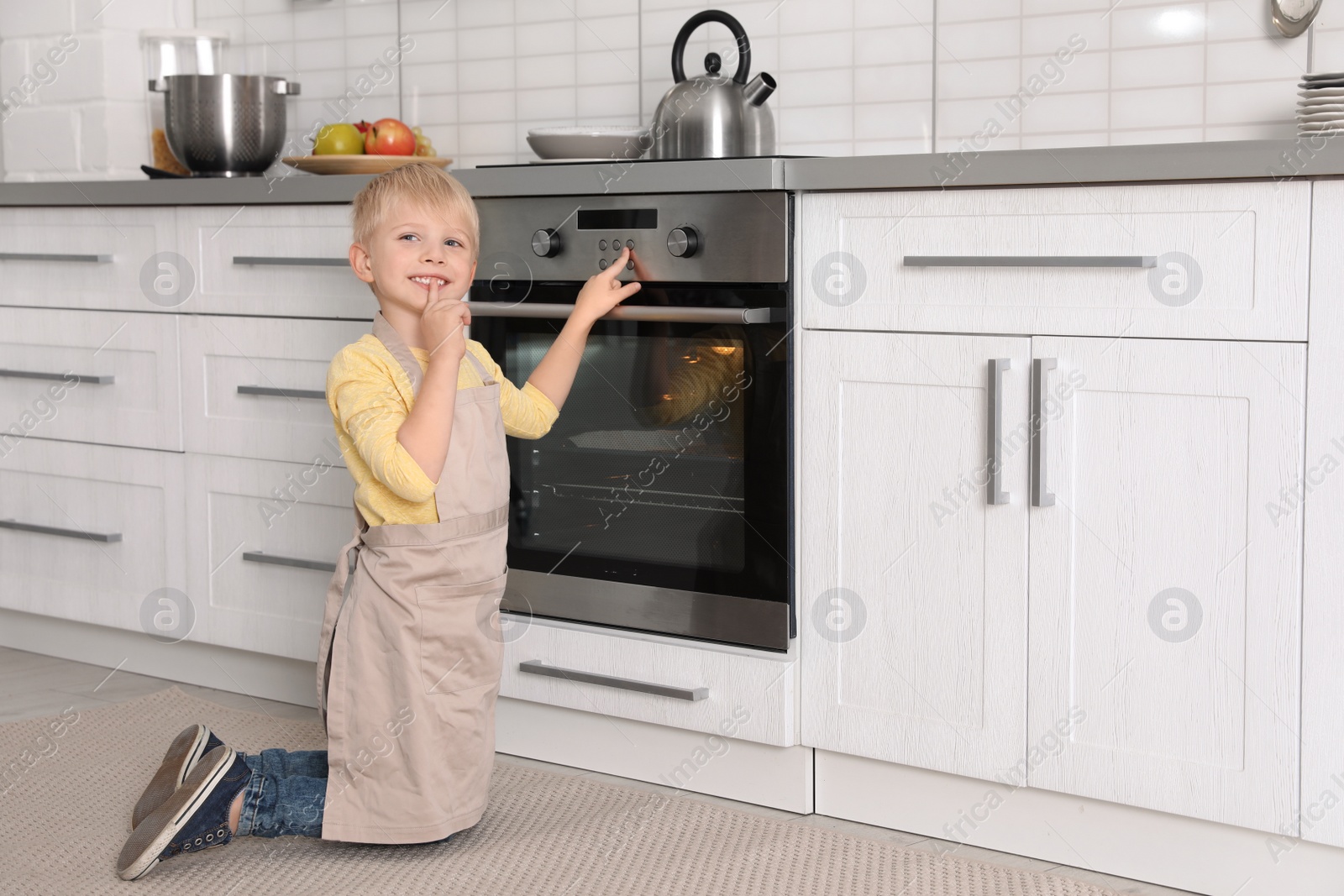 Photo of Little boy baking something in oven at home