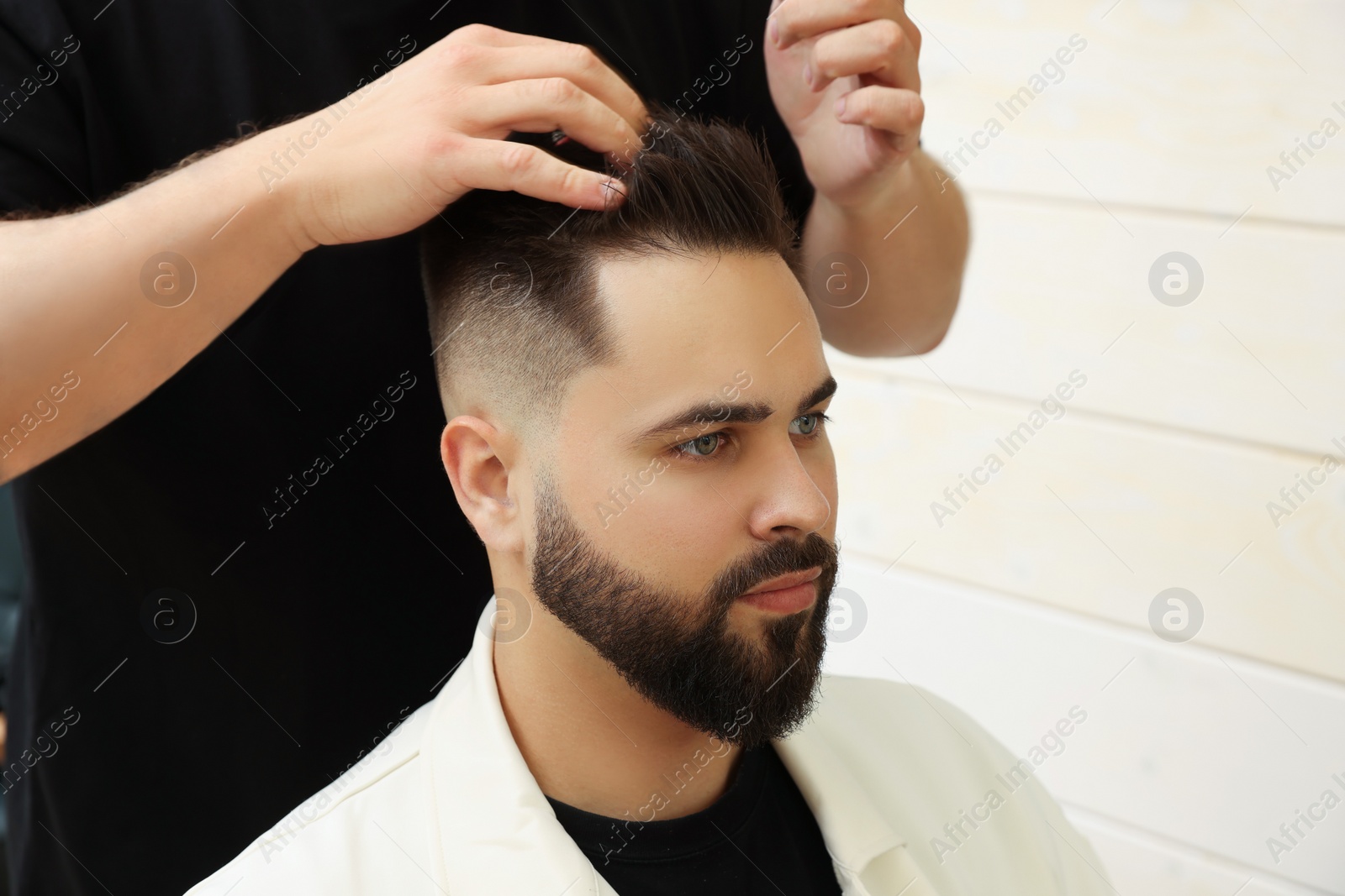 Photo of Professional hairdresser working with client in barbershop, closeup