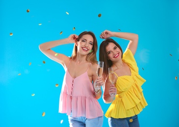 Photo of Portrait of happy friends with champagne in glasses and confetti on color background