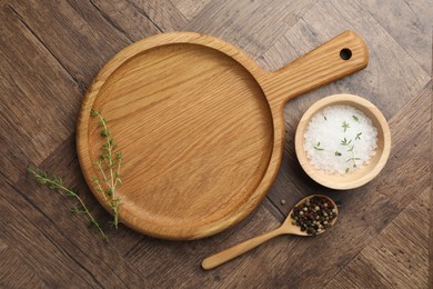 Photo of Cutting board and different spices on wooden table, flat lay